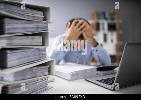 Photo Of Overworked Businessman Doing Taxes At Office Stock Photo