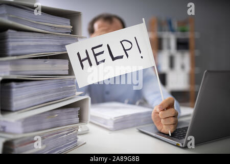 Close-up Of A Businessman Hand Holding Help Flag In Between The Stack Of Folders Stock Photo