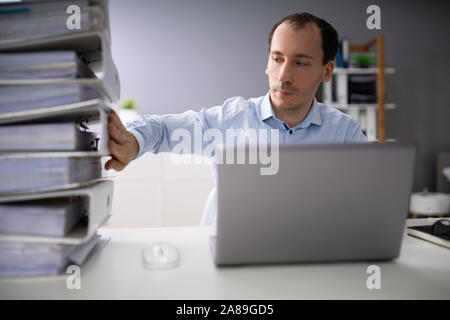 Businessperson Pushing Paper Documents Away And Working With Digital Documents On Computer Instead Stock Photo