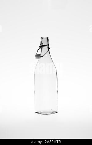 Monochromatic image of a retro empty square glass bottle with an open clip top stopper Stock Photo