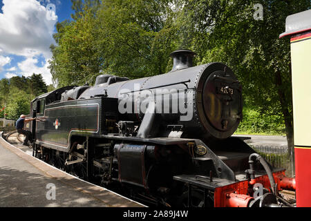 Engineer stepping up to a 1950 black steam engine in Lakeside Station on the Lakeside and Haverthwaite Railway line Cumbria England Stock Photo