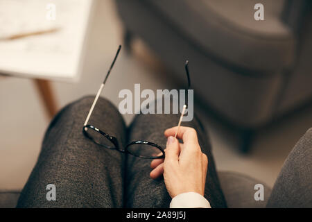 Close-up of businesswoman sitting and holding eyeglasses during business meeting Stock Photo