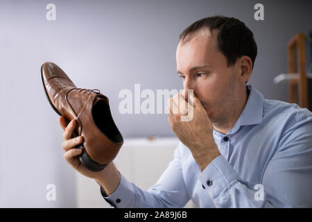 Close-up Of A Young Man Holding Stinky Shoe Stock Photo