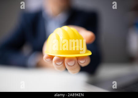 Close-up Of Person's Hand Holding Hard Hat Stock Photo