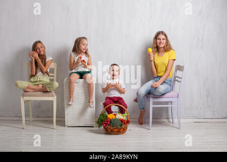 boy and three girls with a basket of vegetables and fruits Stock Photo