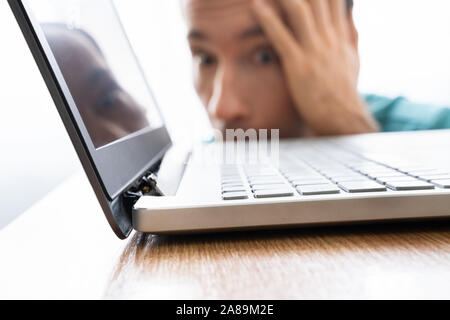 Man Looking At Damaged Laptop Computer With Broken Screen Attachment Stock Photo