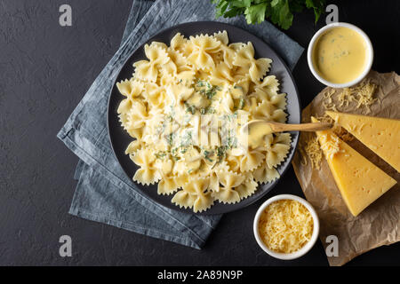Tasty cooked italian farfalle pasta (bow-tie or butterfly) with cheese sauce. Top view. Black background. Stock Photo