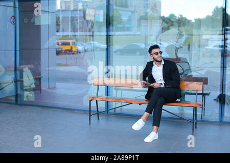 Man in suit arabic puts on sunglasses with tablet near business center Stock Photo