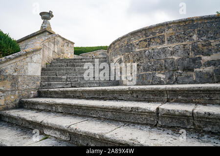 A view of massive old stone stairs leading from one garden into another Stock Photo