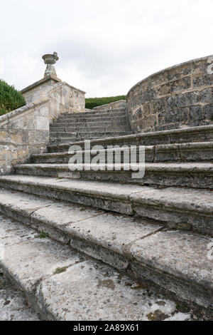 A view of massive old stone stairs leading from one garden into another Stock Photo