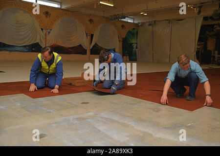 WEST COAST, NEW ZEALAND, JUNE 28, 2019: A team of tradesman lay new carpet squares in a commercial building. Stock Photo