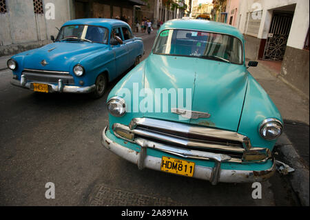 HAVANA - MAY 16, 2011: A classic car passes another parked on a street in Centro. Vintage American cars from the 1950s are found all over Cuba.
