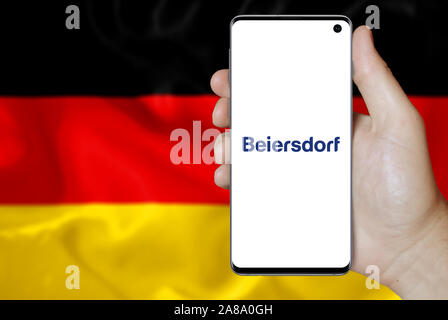 Logo of public company Beiersdorf displayed on a smartphone. Flag of Germany background. Credit: PIXDUCE Stock Photo