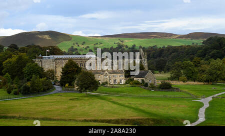 Scenic rural view over ancient, picturesque monastic ruins of Bolton Abbey, Priory Church, Old Rectory & winding path - Yorkshire Dales, England, UK.