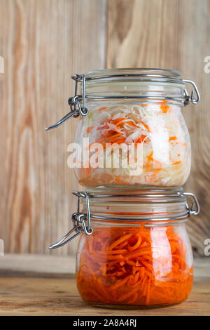 Korean carrots and fermented cabbage in glass jars on a wooden table Stock Photo