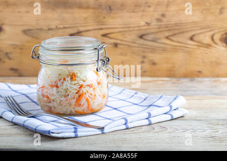 fermented cabbage in plate jars on a white towel on a wooden table Stock Photo