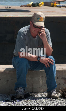 Magnolia Springs Volunteer Fire Department Chief Jamie Hinton fields phone calls as he sits in front of a spud barge in Magnolia Springs, Alabama. Stock Photo