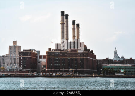 Office, apartments and industrial chimneys buildings in the skyline at sunset, from Hudson river. Pollution and industry concept. Manhattan, New York Stock Photo