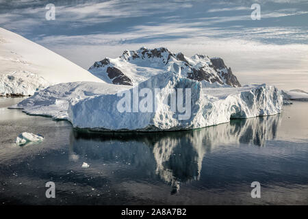 Iceberg and mountain backdrop near the Lemaire Channel along the Antarctic Peninsula. Stock Photo