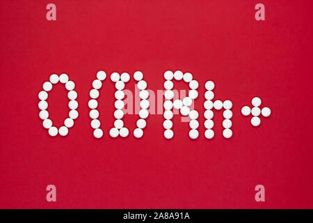 First blood type. Blood type symbol from white pills on a red background. Blood type treatment. Stock Photo