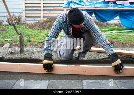 Man Screeding Sand for Patio Paver Stones, Authentic Construction, MR Stock Photo