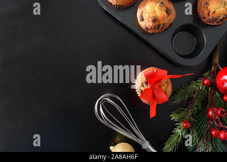 Background with freshly muffins for the christmas holidays on black table. Horizontal composition. Top view. Stock Photo