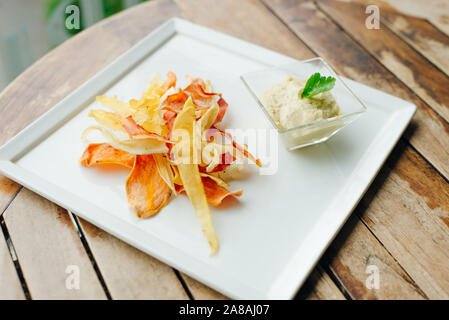 hummus with root vegetable color chips in restaurant Stock Photo