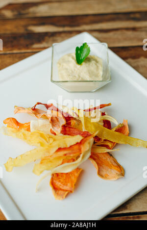 hummus with root vegetable color chips in restaurant Stock Photo