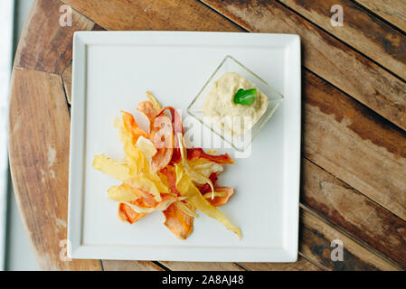 hummus with root vegetable color chips in restaurant Stock Photo