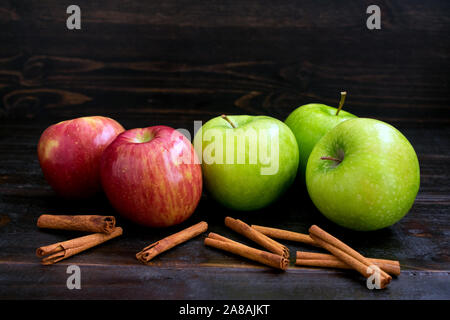 Granny Smith and Fuji apples with cinnamon sticks on a dark wood background Stock Photo
