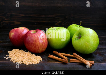 Granny Smith and Fuji apples with cinnamon sticks on a dark wood background Stock Photo