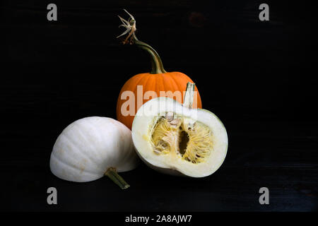 Raw white pumpkin that has been cut in half with an orange pie pumpkin in the background Stock Photo