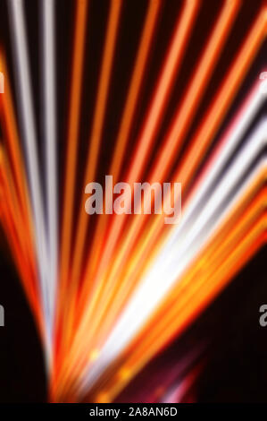Blurred, no focused, abstract festive vertical background with red, orange and white neon led stripes on a black background, creative workspace for de Stock Photo