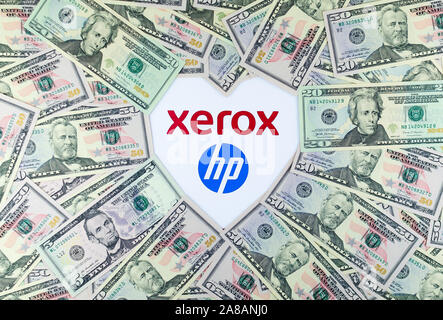 XEROX and HP logos on the paper brochure and dollar bills placed around in a shape of heart. Illustrative for the news about potential merger.