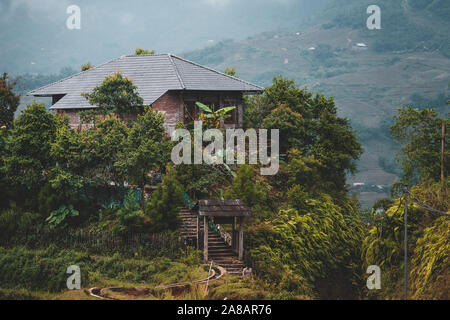 Houses and homes on top of Rice terraces outside the beautiful village of Sapa in Northern Vietnam, surrounded by mountains Stock Photo
