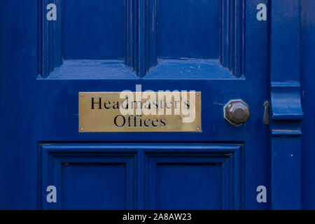 A brass sign reading Headmasters offices on a old blue door with a brass handle Stock Photo