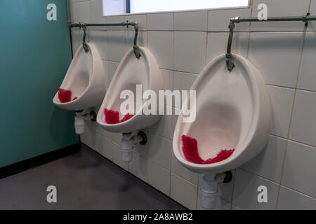three urinals in a men's public bathroom or men's public toilet
