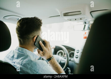 transport, business trip, technology and people concept - close up of young man with smartphone driving car Stock Photo