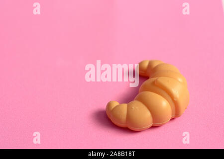 Toys for kids in food theme. One Croissant on isolated background. Food and toy concept. Object made from plastic. Stock Photo