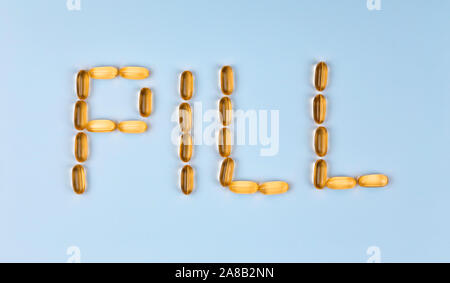 The word Pill is laid out with tablets. The word Pill is laid out with gel pills on a blue background with copy space for text Stock Photo