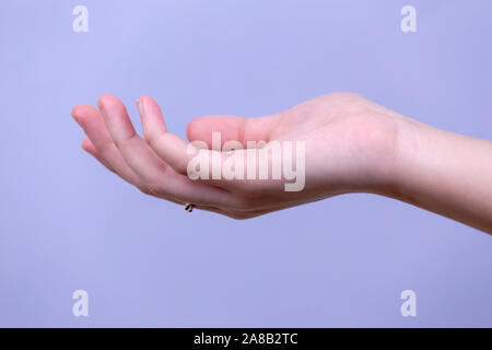 Young woman's stretched skinny arm and open palm holding imaginary