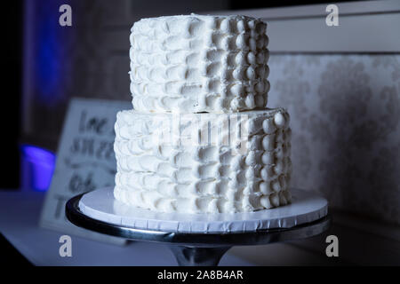A simple layered cake with whipped frosting on top of a cake stand. Stock Photo