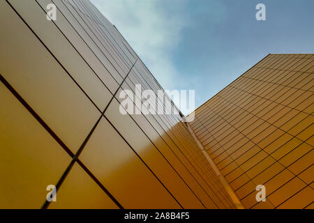Wall of a high-rise building faced with yellow tiles against the sky. Bottom view. Stock Photo