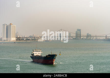 Da Nang, Vietnam - March 10, 2019: Tien Sa Port in Da Nang Bay. Binh Nguyen bulk cargo ship leaves harbor. Thuan Phuoc suspenstion bridge and cityscap Stock Photo