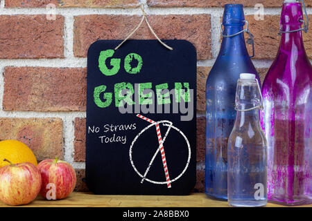 Chalkboard notice, Go Green, No straws today with no straws symbol, on table with water bottles and fruit, ban on single use plastics concept for sust Stock Photo