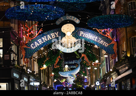 The crowds packed Carnaby street to see Ronnie Wood turn the lights on. The theme this year is Save the Planet by Project Zero. They are an ocean conservation charity and they created an eco friendly display. All the decorations are made out of recycled material. Stock Photo