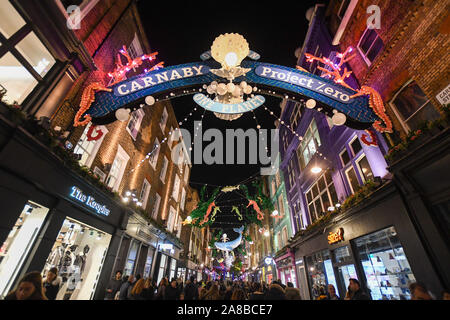 The crowds packed Carnaby street to see Ronnie Wood turn the lights on. The theme this year is Save the Planet by Project Zero. They are an ocean conservation charity and they created an eco friendly display. All the decorations are made out of recycled material. Stock Photo
