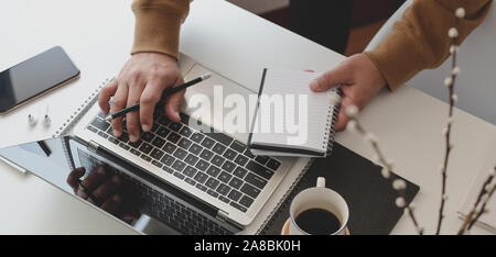 Cropped shot of male freelancer working on his project while collecting ideas from notebook in comfortable workspace Stock Photo