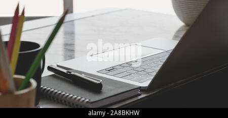 Close-up view of comfortable workplace with laptop computer and office supplies near the windows Stock Photo