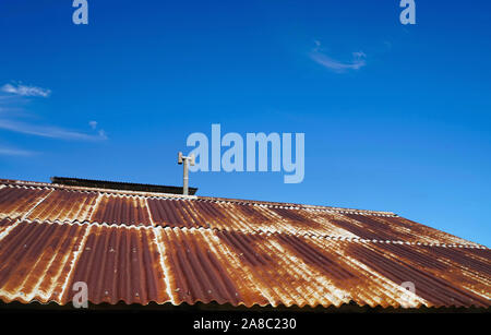 old rusty roof with chimney and blue sky in the background Stock Photo